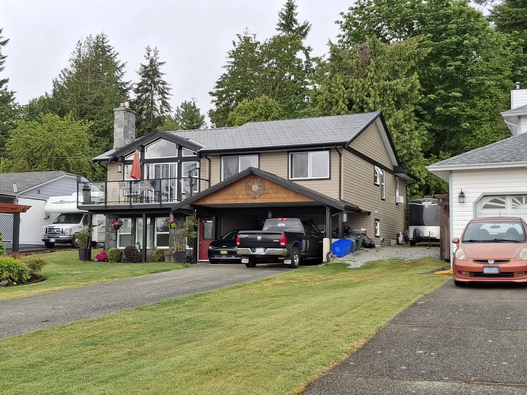 Black Interlock Slate aluminum roof on a brown two-storey home with dormers among tall trees, Chemainus, British Columbia
