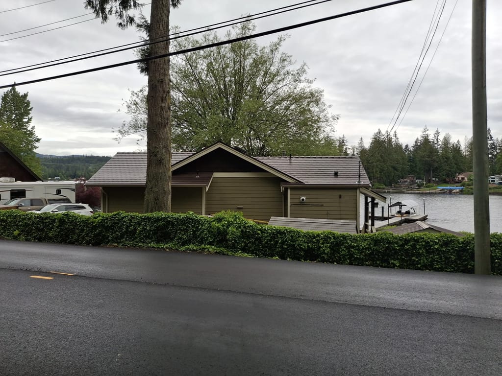 Colonial Brown Interlock Slate aluminum roof on a colonial home with a brown roof among tall trees and water, Shawnigan Lake, British Columbia