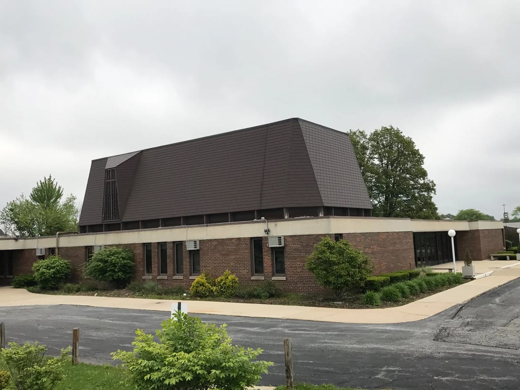 White Interlock IB Membrane aluminum roof on a brown brick home with a metal roof among trees and houses, Chicago Heights, Illinois