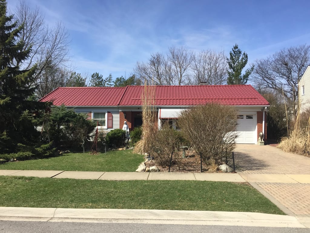 Tile Red Interlock Tile aluminum roof on a red metal roofed ranch home among tall trees, Schaumburg, Illinois