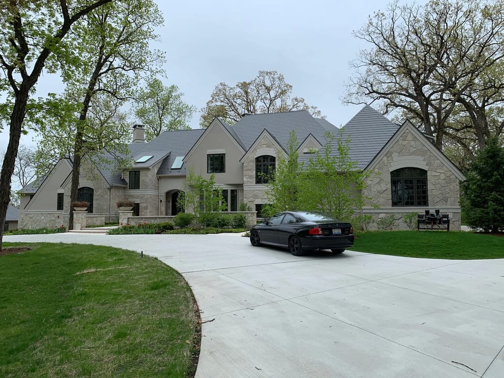 Musket Grey Interlock Slate aluminum roof on a grey two-storey home with dormers among tall trees, Long Grove, Illinois