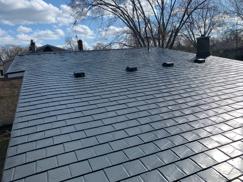 Deep Charcoal Interlock Slate aluminum roof on a single-story home with a metal roof among bare trees, Waukegan, Illinois