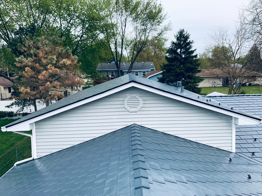 Deep Charcoal Interlock Slate aluminum roof on a white home with a metal roof among green trees, Elgin, Illinois