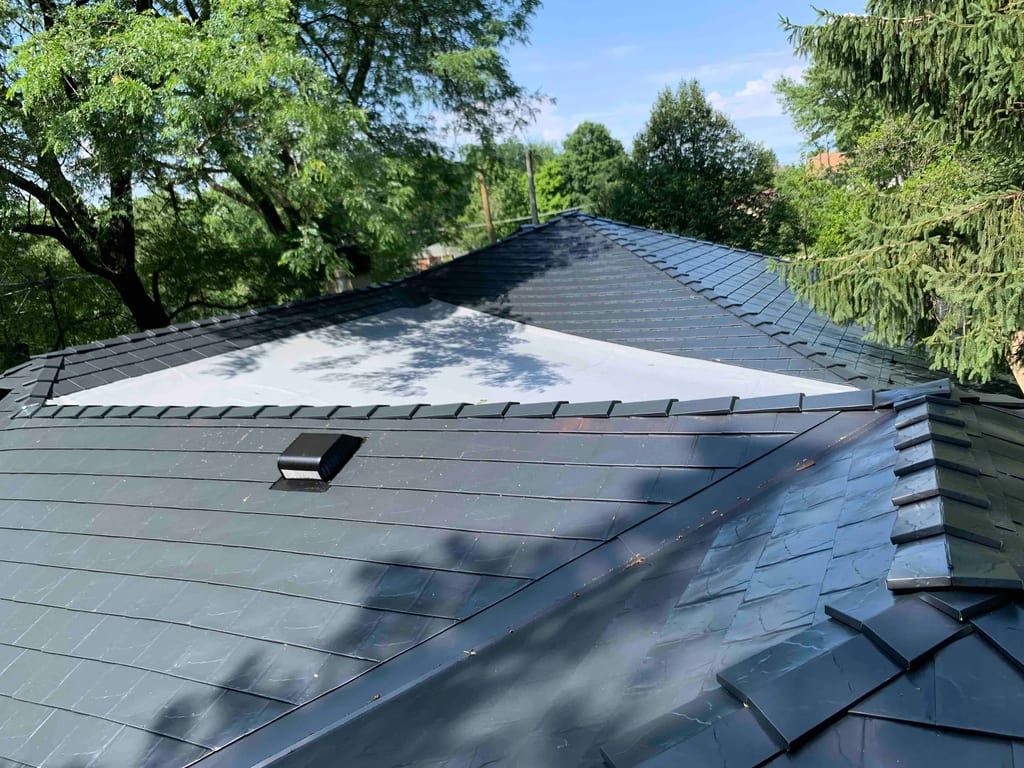 Black Interlock Slate aluminum roof on a black single-family home among tall trees in a suburban, Lombard, Illinois
