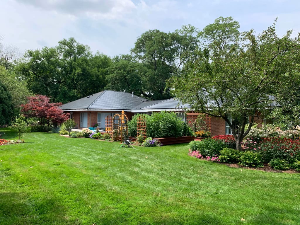 Black Interlock Slate aluminum roof on a red brick home with a grey metal roof surrounded by green, Flossmoor, Illinois