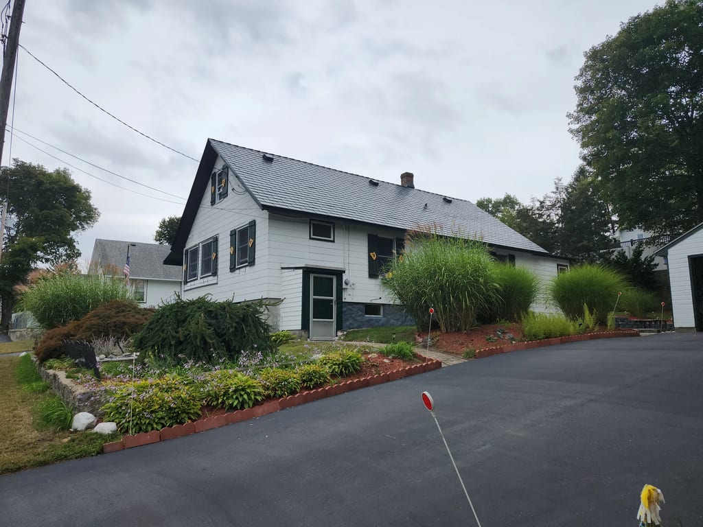 Hunter Green Interlock Shingle aluminum roof on a white two-storey ranch with a grey roof and dormers, Dracut, Massachusetts