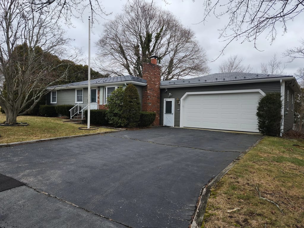 Charcoal Grey Interlock Shingle aluminum roof on a grey single-storey home with garage among bare trees, Somerset, Massachusetts