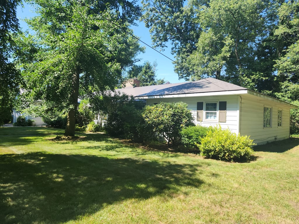 Weathered Interlock Slate aluminum roof on a white ranch home with a metal roof among tall green trees, Longmeadow, Massachusetts