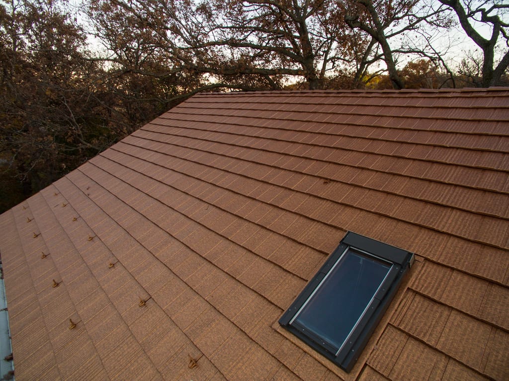 Aged Copper Interlock Shake aluminum roof on a two-storey home with an aged copper metal roof among tall, Bloomington, Minnesota
