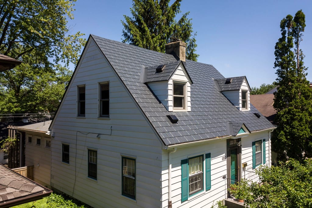 Deep Charcoal Interlock Slate aluminum roof on a white two-storey Cape Cod home among tall trees, St Paul, Minnesota
