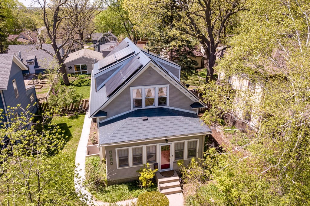 Deep Charcoal Interlock Slate aluminum roof on a grey two-storey cottage with dormers among tall trees, Minneapolis, Minnesota