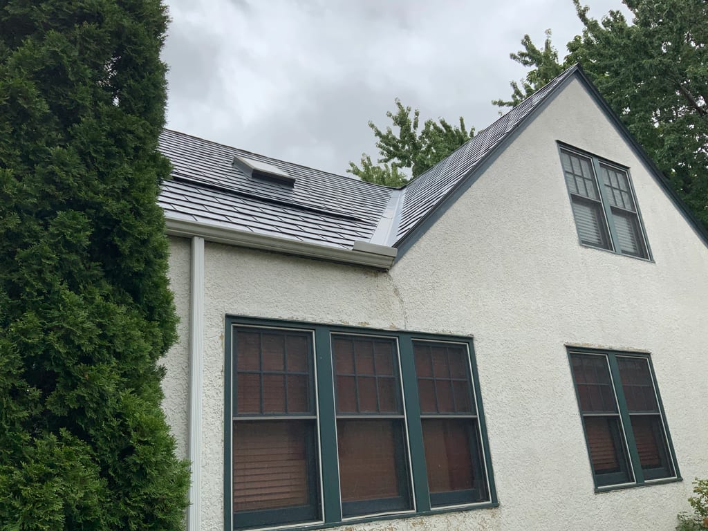 Deep Charcoal Interlock Slate aluminum roof on a white two-storey colonial home with dormers in a forested, Saint Paul, Minnesota