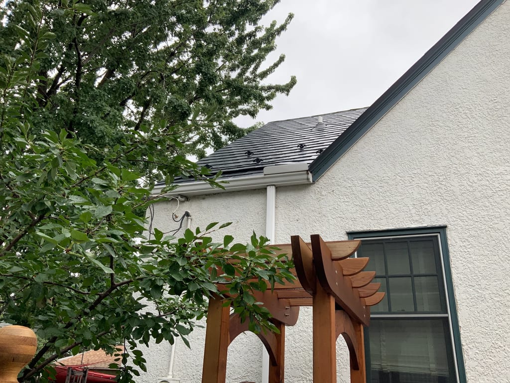 Deep Charcoal Interlock Slate aluminum roof on a white home with a metal roof and a tree in front, Saint Paul, Minnesota