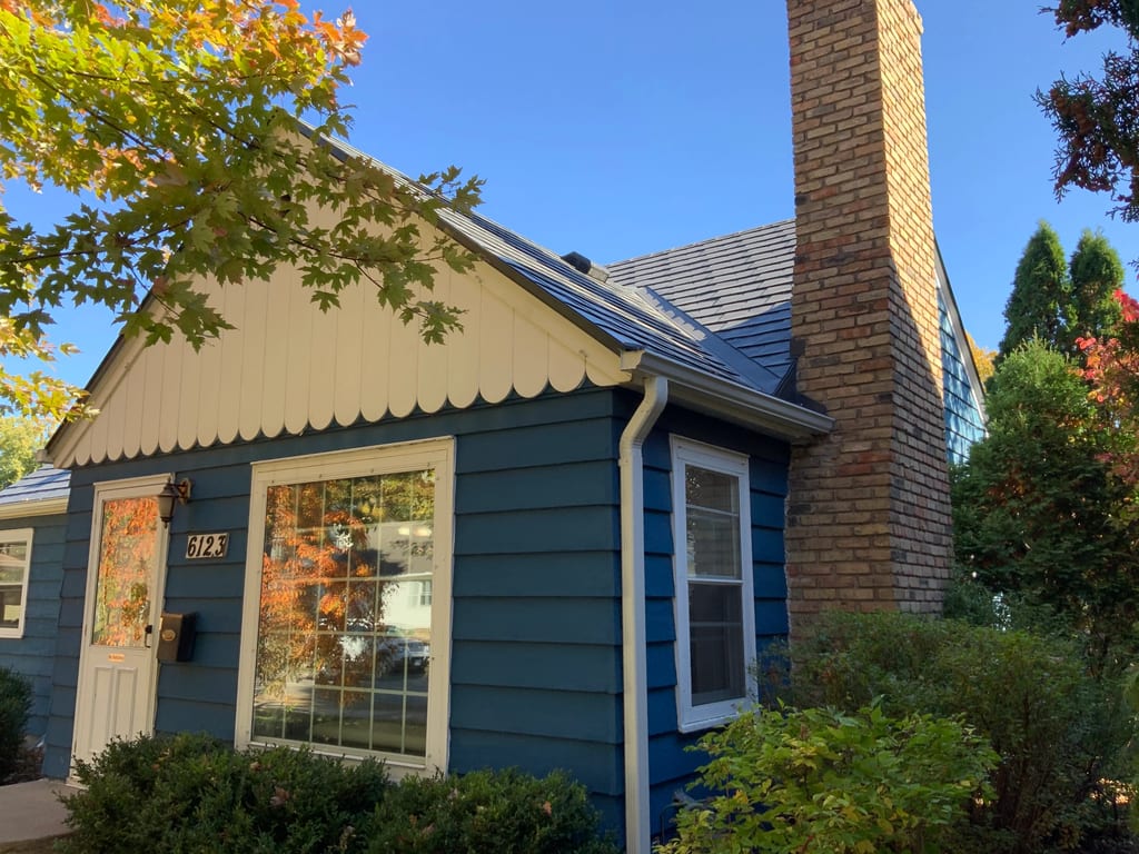 Deep Charcoal Interlock Slate aluminum roof on a blue home with a gable and chimney in a wooded suburban, Minneapolis, Minnesota