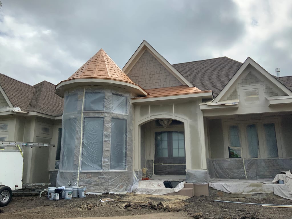 Copper Penny Interlock Slate aluminum roof being installed on a beige single-family home under construction in a rural, Prior Lake, Minnesota