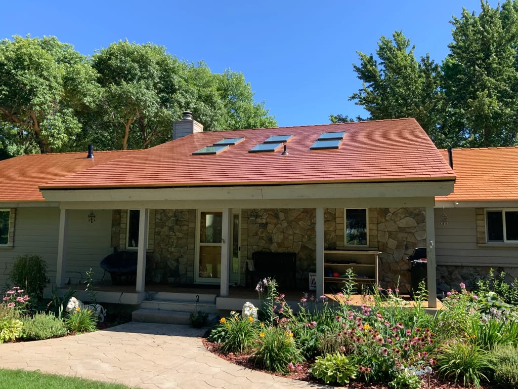 Copper Penny Interlock Slate aluminum roof on a beige ranch style home with stone facade in a wooded, Shorewood, Minnesota