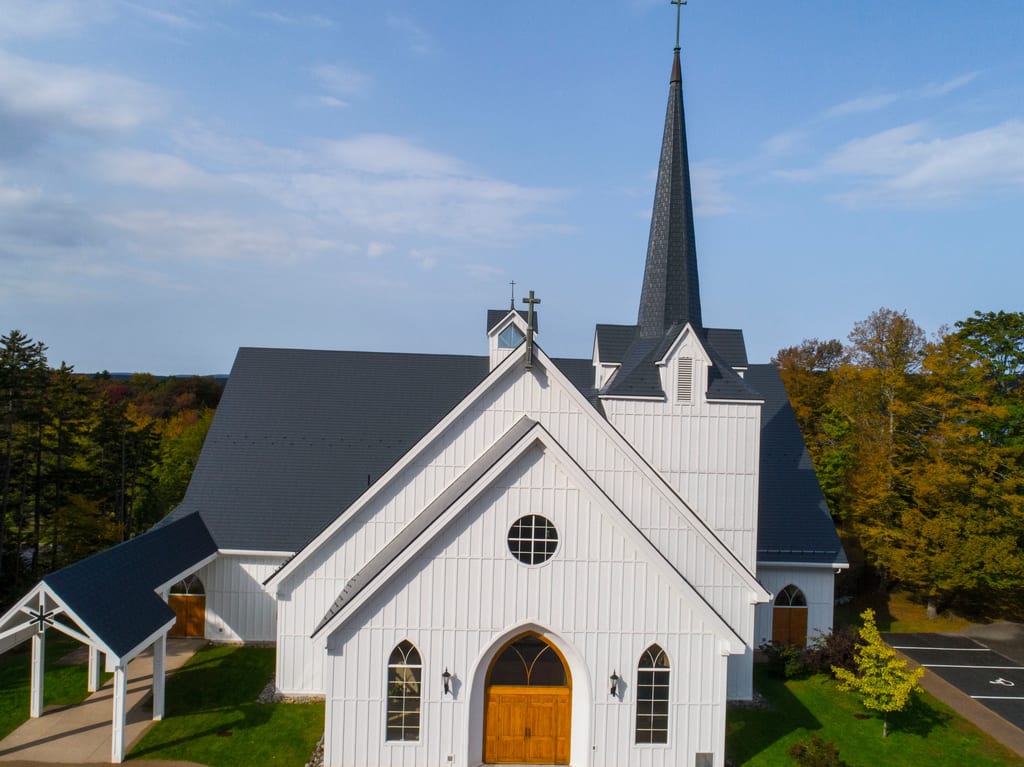 Deep Charcoal Interlock Slate aluminum roof on a white church with a metal roof among tall green trees, Rothesay, New Brunswick