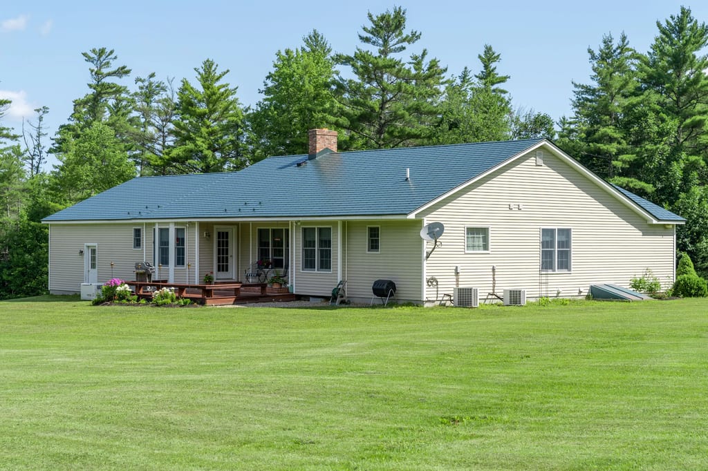 Hunter Green Interlock Slate aluminum roof on a hunter green ranch home with a metal roof in a forested, Sanbornville, New Hampshire