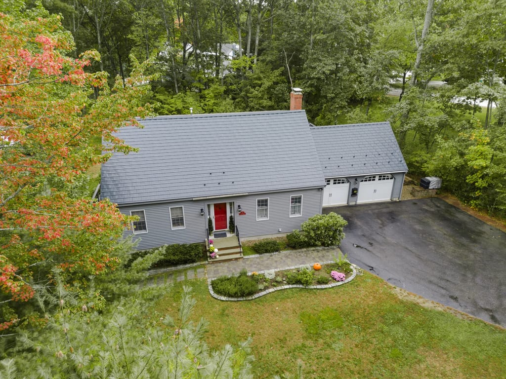 Black Interlock Slate aluminum roof on a grey single-family home with a metal roof among trees, Rochester, New Hampshire