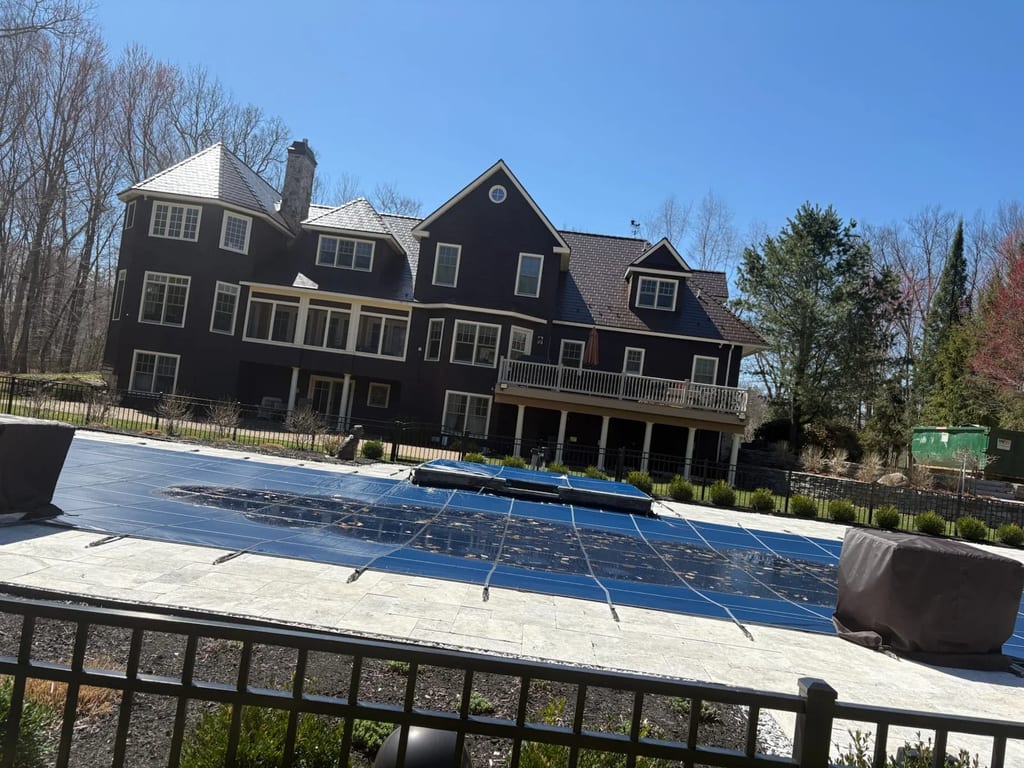 Colonial Brown Interlock Slate aluminum roof on a brown Colonial home with dormers among tall pines, Concord, New Hampshire