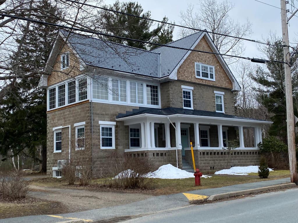 Deep Charcoal Interlock Slate aluminum roof on a brown two-storey home with dormers on a snow-covered, Mahone Bay, Nova Scotia