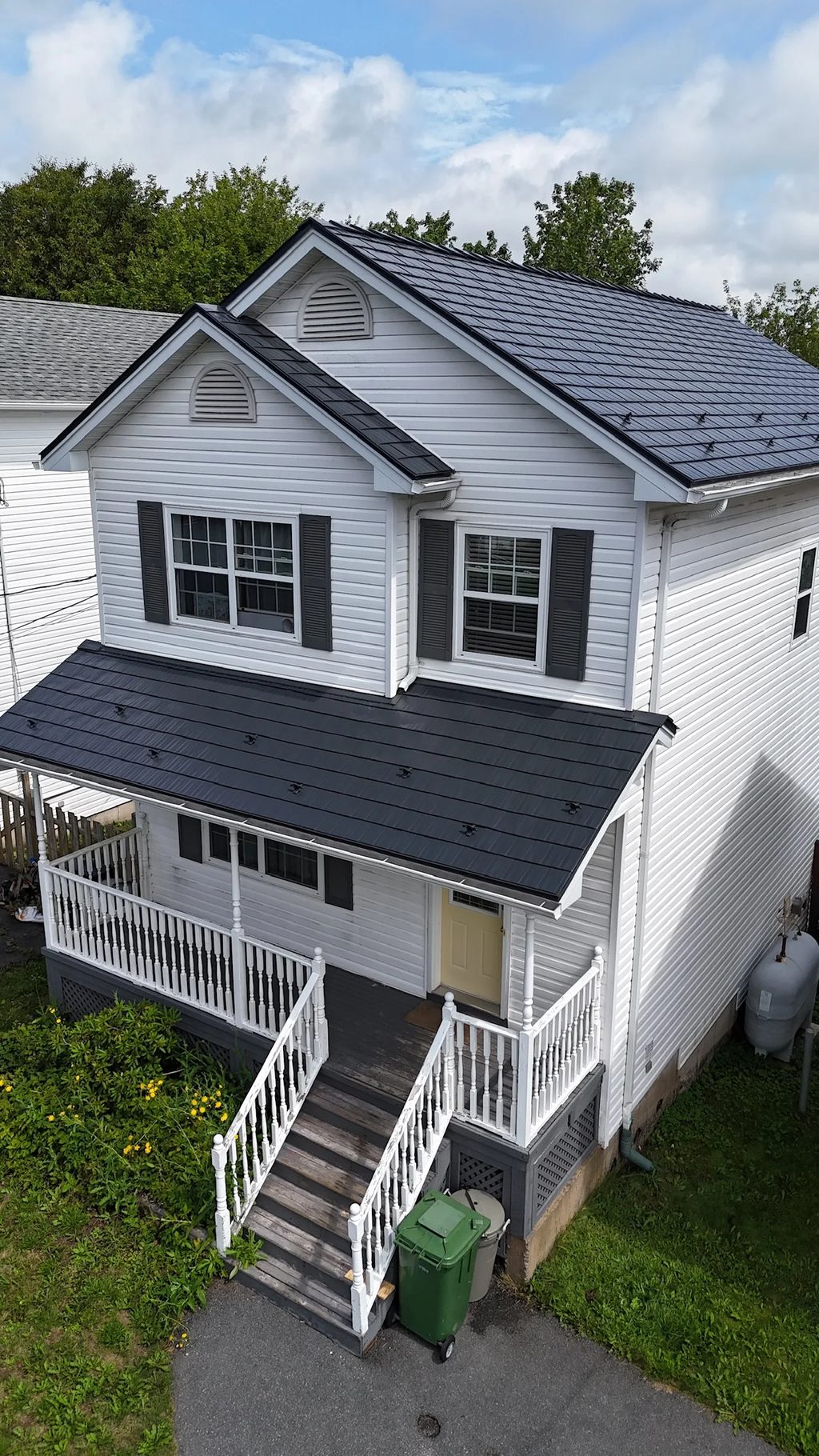 A white colonial home with a black metal roof and a skylight