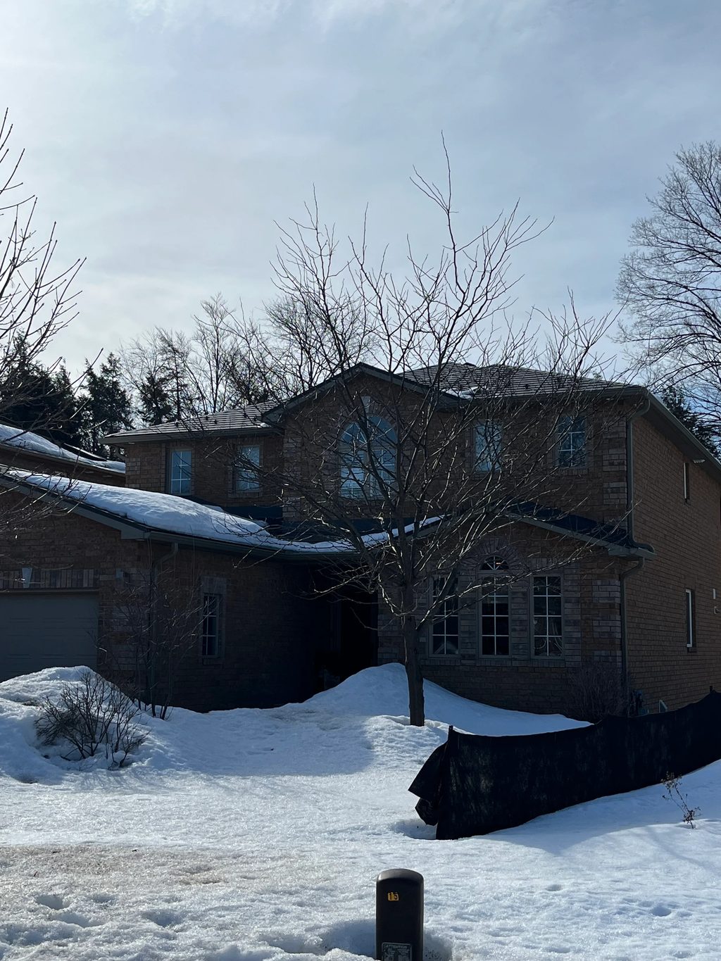 Musket Grey Interlock Slate aluminum roof being installed on a two-storey home in a forested area with snow on the ground, Barrie, Ontario