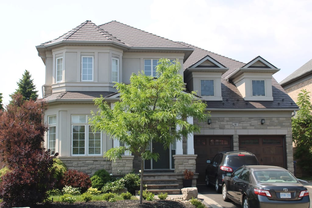 Tudor Brown Interlock Cedar Shingle aluminum roof on a Tudor brown two-storey home with dormers among tall pines, Brampton, Ontario