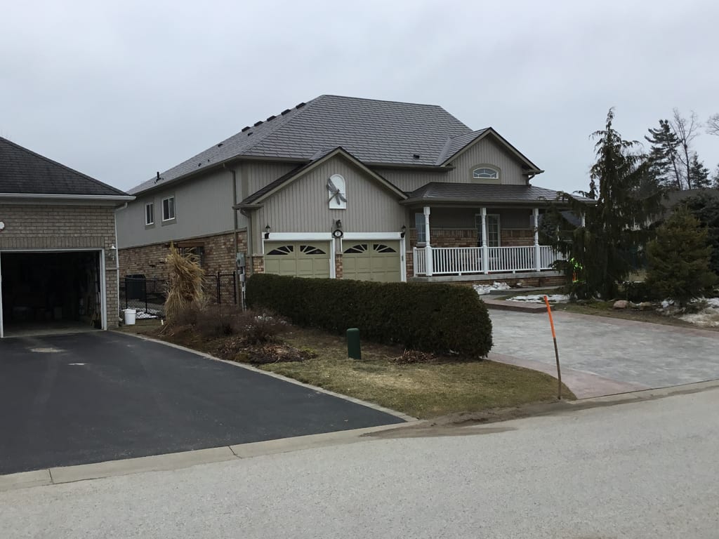 Craftsman-style home in Wasaga Beach with Interlock Tudor Brown aluminum slate roofing, multi-hip complex roof, covered front porch, and double garage.
