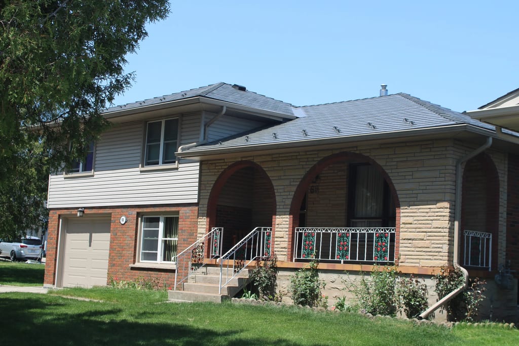 Musket Grey Interlock Cedar Shingle aluminum roof on a beige ranch home with a metal roof among trees, Guelph, Ontario