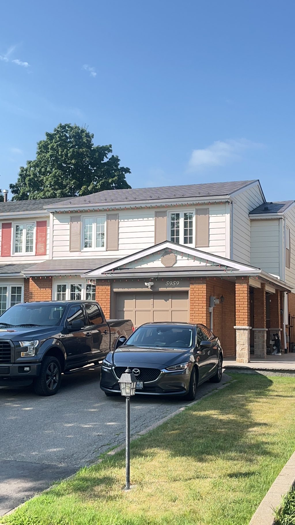 Front elevation of a two-storey townhome in Mississauga with Interlock Musket Grey aluminum slate metal roofing on a multi-plane gabled roof.