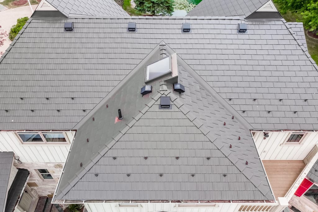 Tudor Brown Interlock Cedar Shingle aluminum roof on a Tudor-style home with a grey metal roof in a forested, Pefferlaw, Ontario
