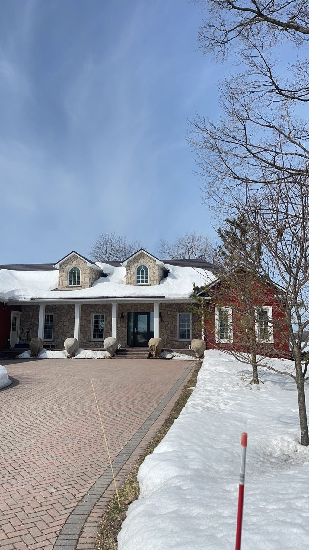 Tudor Brown Interlock aluminum slate roof with twin dormers on a 1.5-storey stone Colonial home in Orillia, ON, photographed in winter.