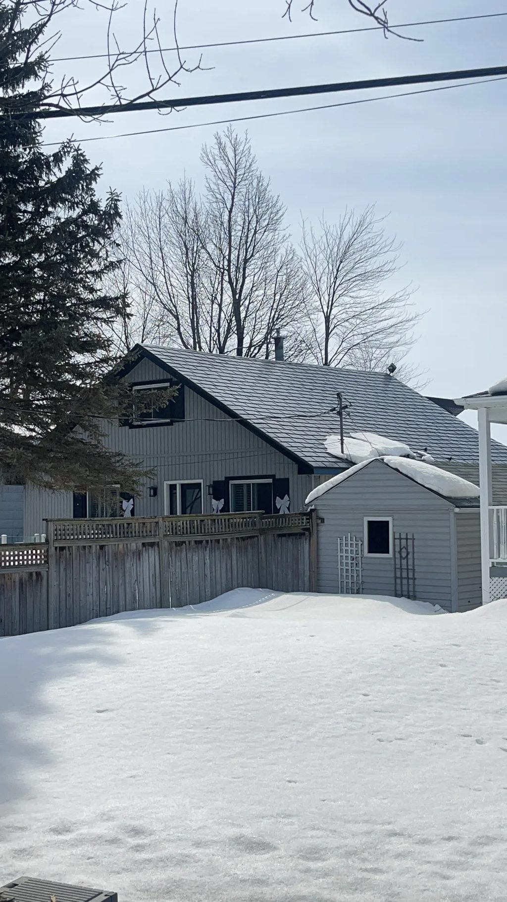 Deep Charcoal Interlock Slate aluminum roof on a grey home with a metal roof among tall trees, Ramara, Ontario