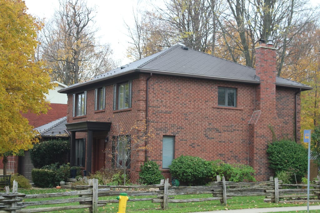 Tudor Brown Interlock Cedar Shingle aluminum roof on a Tudor brown two-storey home with dormers among tall trees, Waterloo, Ontario
