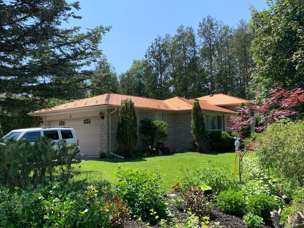 Single-storey ranch home in Aurora, ON with Interlock Copper Penny cedar-shingle aluminum roof over multi-hip roofline, surrounded by mature trees.