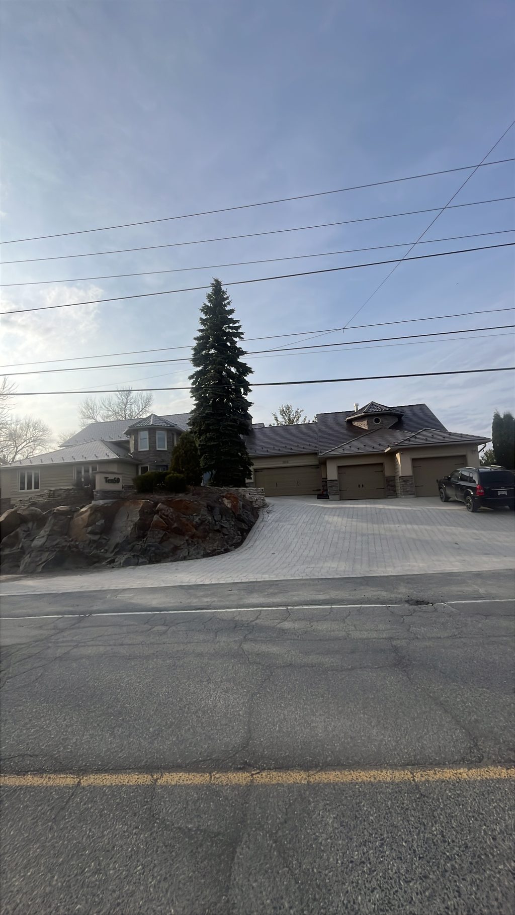 Street-view of a large suburban home in Sudbury with Interlock Colonial Brown aluminum slate roofing across a complex multi-hip profile with turret feature.