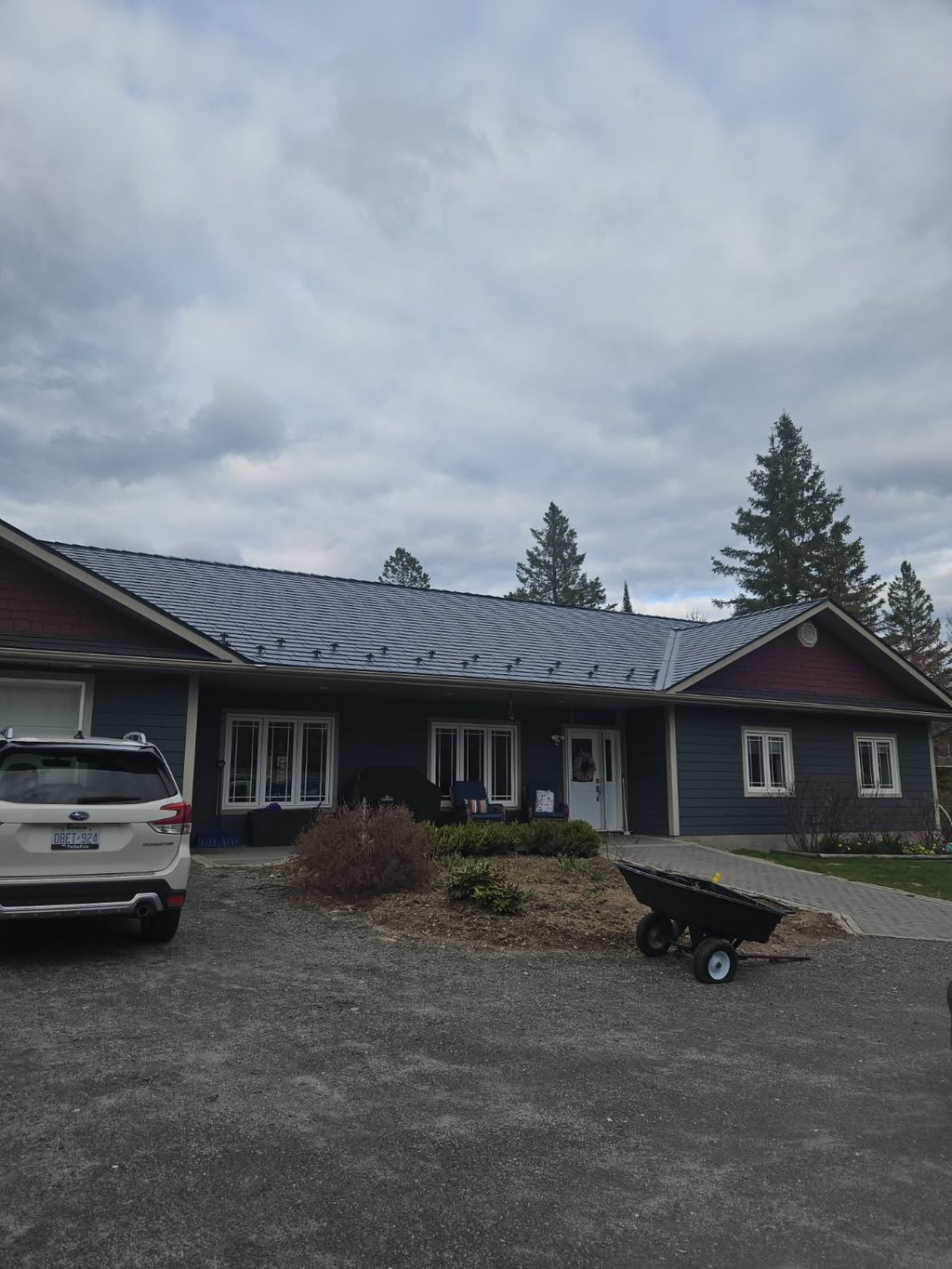 Front elevation of a single-storey ranch home in Sudbury, ON featuring Interlock deep charcoal cedar shingle aluminum metal roofing with snow guards.