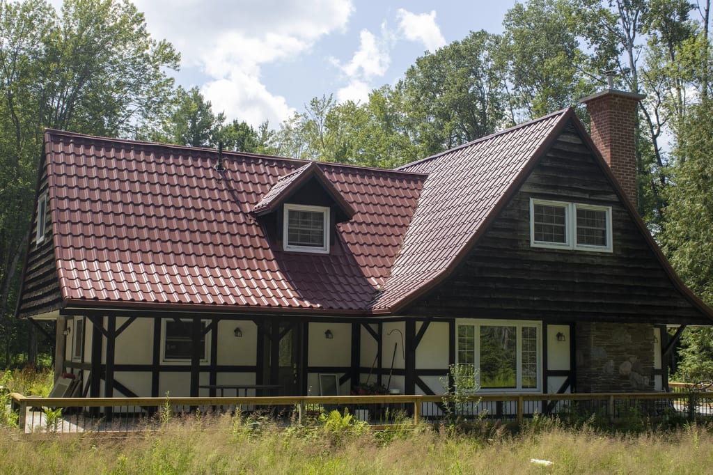 Tile Red Interlock Tile aluminum roof on a red roofed chalet with a porch and tall trees, Gravenhurst, Ontario