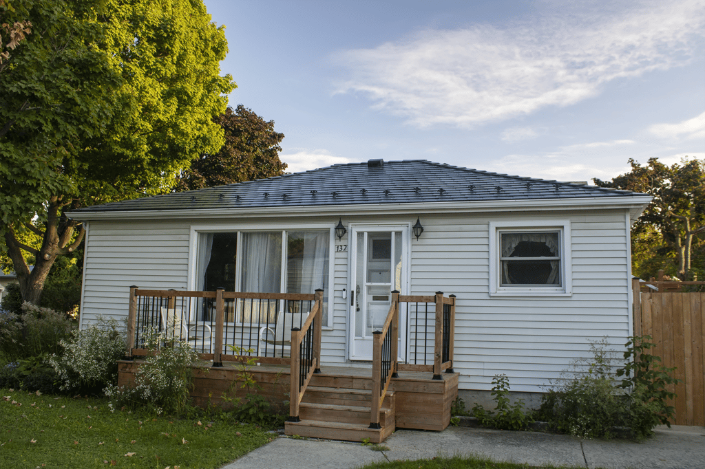 Single-storey ranch-style home in Kingston ON with a low-pitch hip roof clad in deep charcoal Interlock aluminum slate tiles and a new cedar front deck.