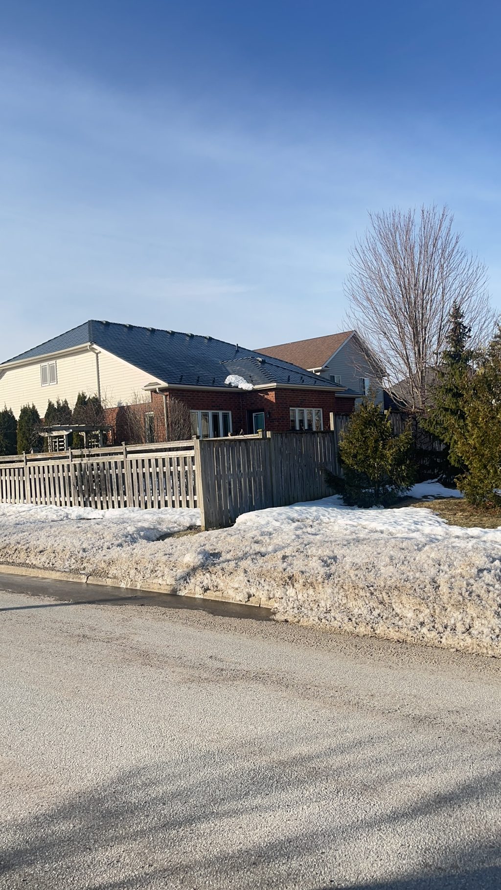 Black Interlock aluminum slate metal roof on a 1-storey brick ranch home in Collingwood, ON, viewed from the street in winter.