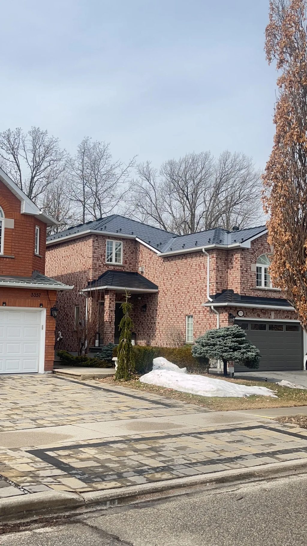 Black Interlock Slate aluminum roof on a red brick two-storey home with dormers among tall trees, Mississauga, Ontario