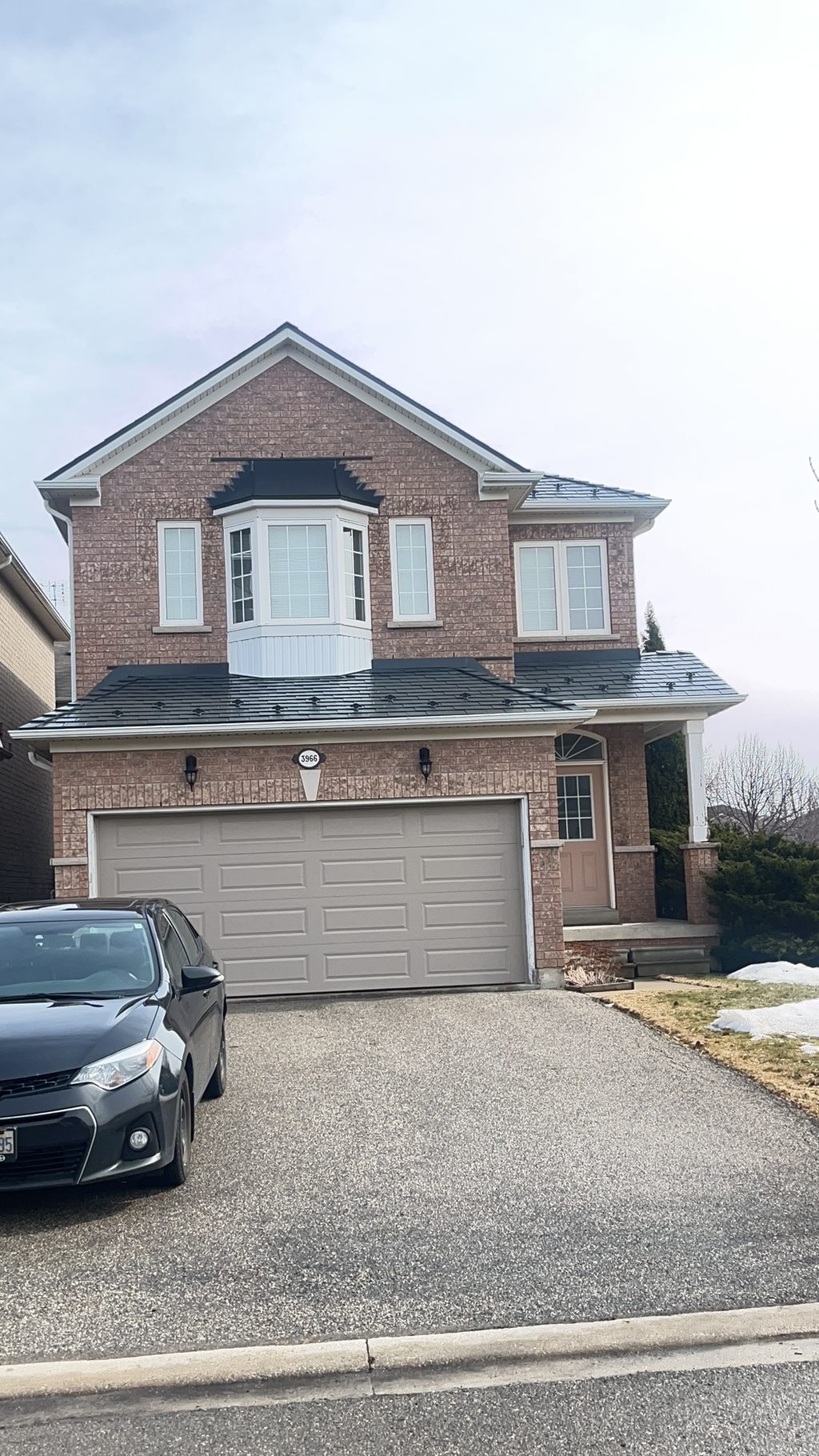 Two-storey brick home in Mississauga with Interlock deep charcoal aluminum slate metal roofing covering a multi-plane complex roof with bay window.