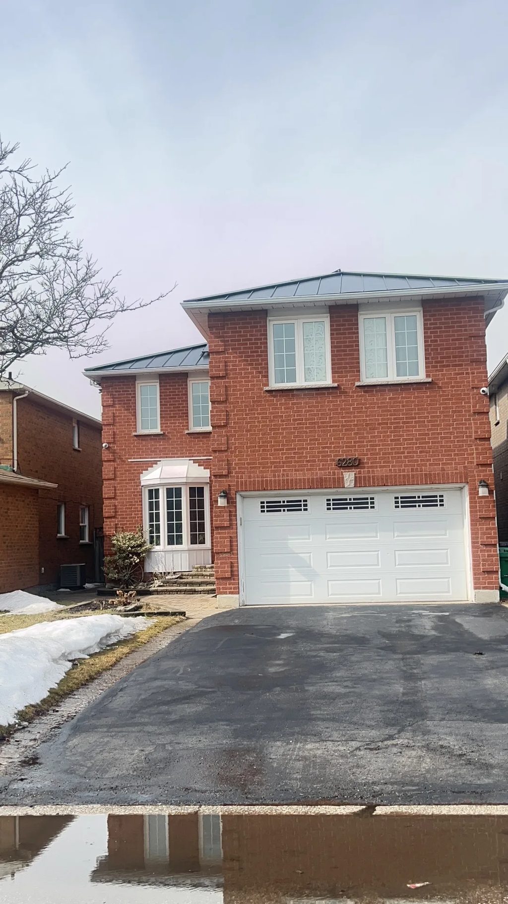 Black Interlock Standing Seam aluminum roof being installed on a red brick house with a metal roof in an urban/suburban, Mississauga, Ontario