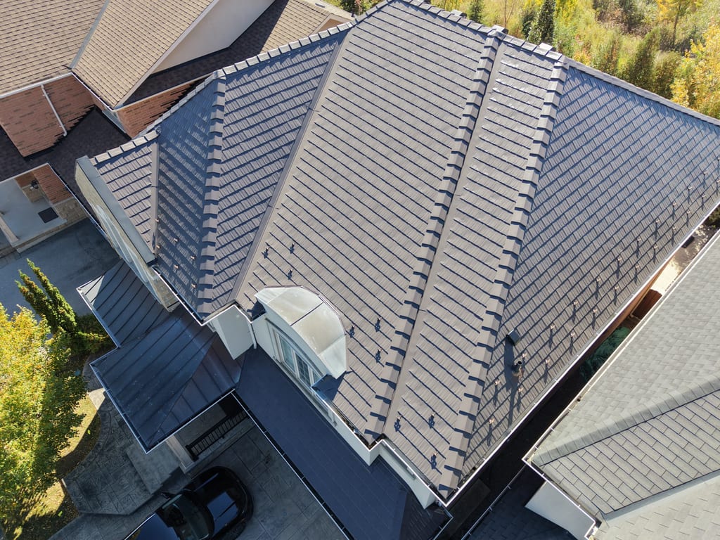Tudor Brown Interlock Cedar Shingle aluminum roof on a grey house with a Tudor roof among tall trees, Oakville, Ontario