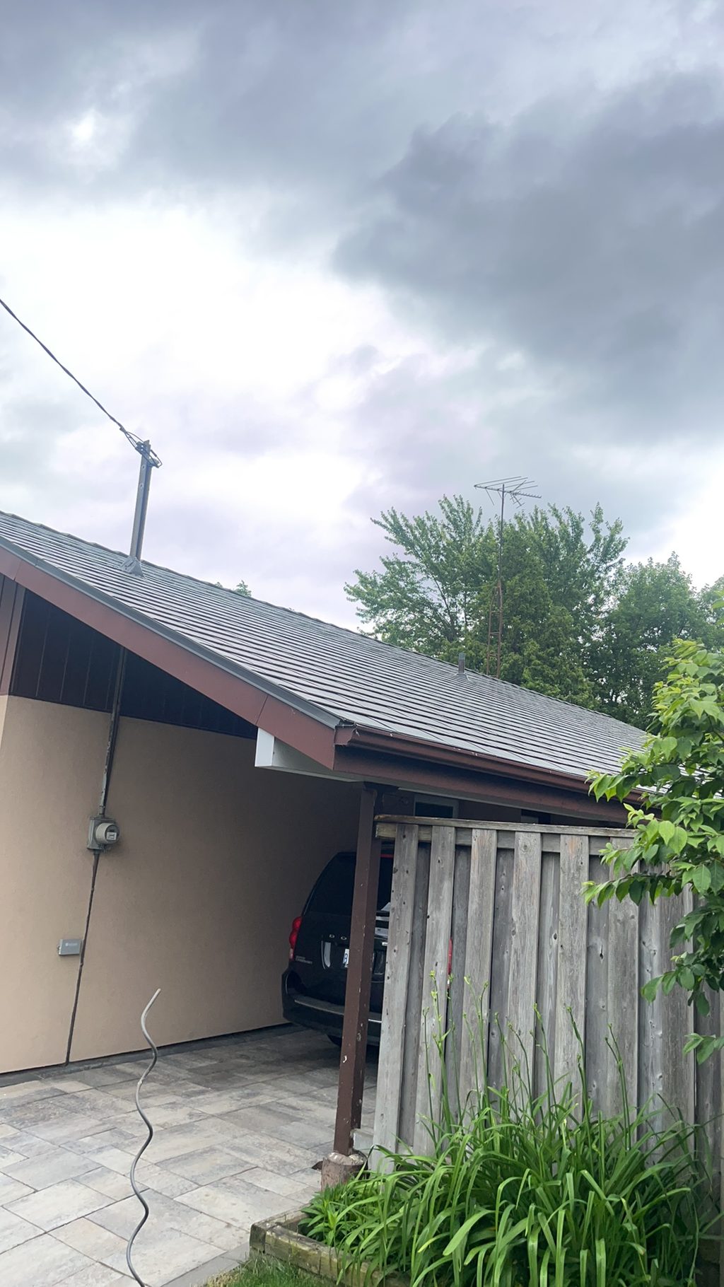 Low-slope gable ranch home in Scarborough with Interlock Musket Grey aluminum slate metal roofing, viewed from front-right under overcast skies.