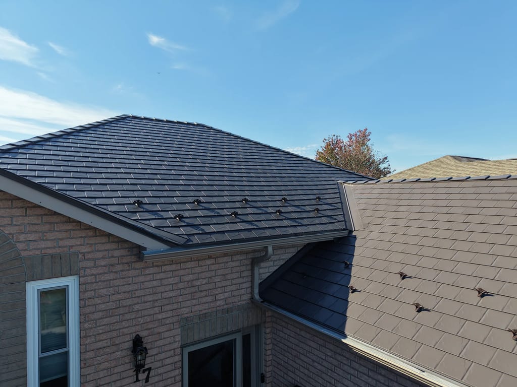 Tudor Brown Interlock Slate aluminum roof on a brown single-family Tudor home among tall pines, Lindsay, Ontario