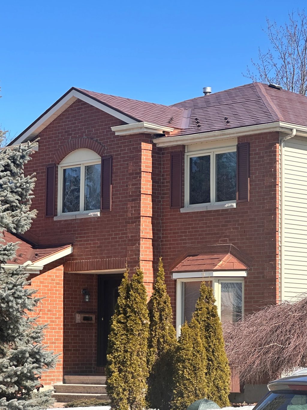 Aged Copper Interlock Shingle aluminum roof on a red brick two-storey home with dormers among tall pines, Orléans, Ontario