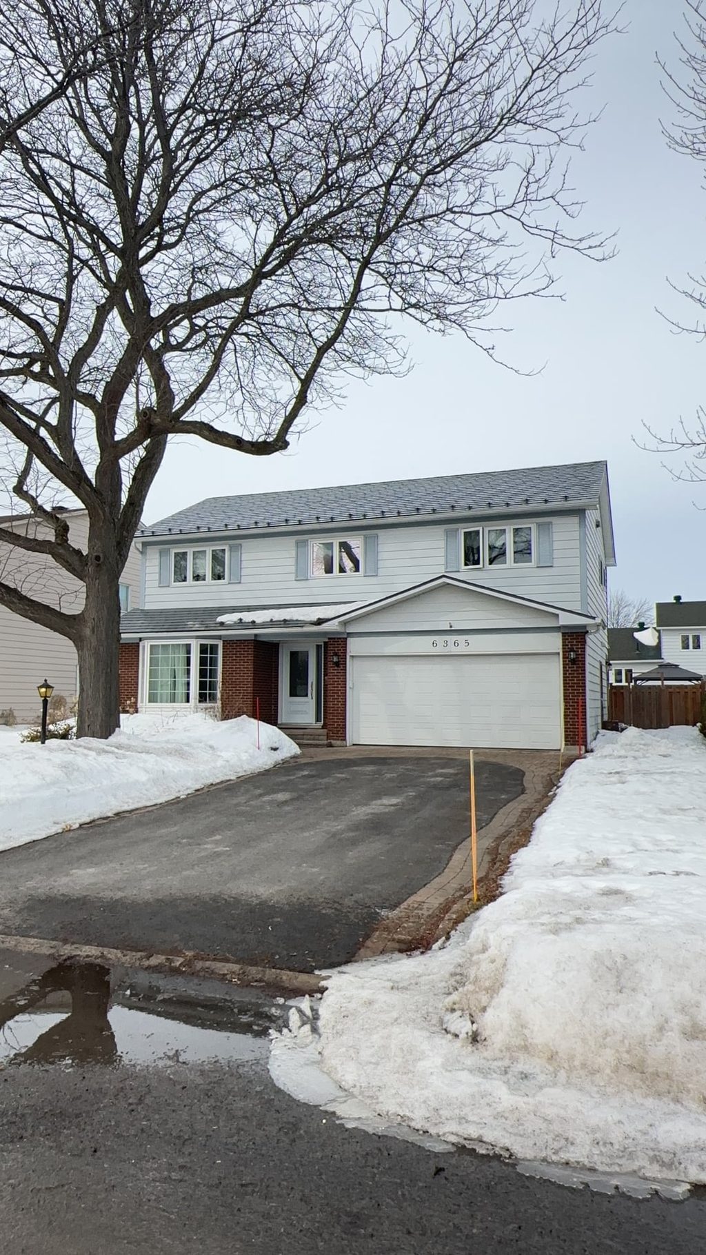 Two-storey colonial-style home in Orleans ON with Interlock charcoal grey aluminum slate metal roofing, brick lower facade, and attached garage.
