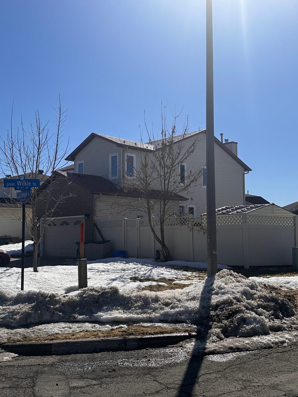 Two-storey suburban colonial home in Orleans ON with Interlock aluminum shingle roofing in Tile Red, viewed from street corner in winter.